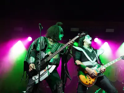 two rock performers playing guitar on stage