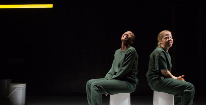 Two people sitting on white buckets on a black background