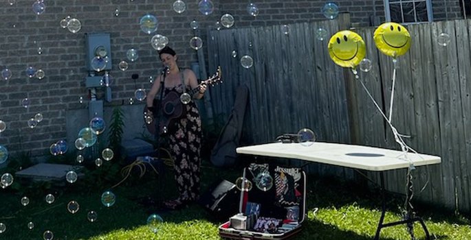 Performer singing and playing guitar in backyard