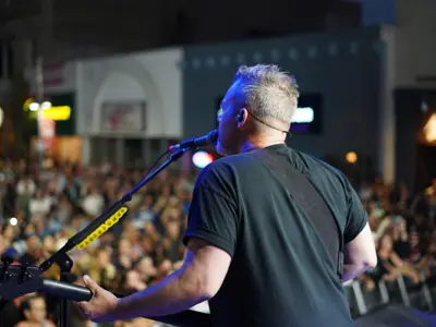 musician singing in mic with large crowd in background