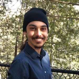 Man wearing a beanie in a forest looking at the camera