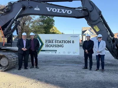 Mayor and councillors posing with work vehicles in front of fire house construction