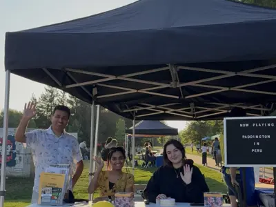 Councillor posing at booth with  youth at public outdoor event
