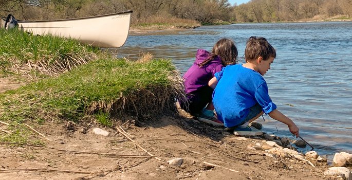 Two kids playing at edge of river